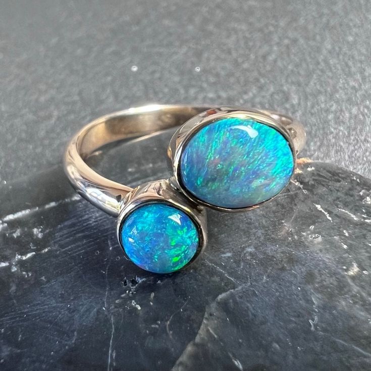 Two stone Australian opal ring set in solid 14k gold.  Double opal ring, with dark opal and crystal opal in 14k yellow gold. US Size 6 1.05 total carats Australian opal from Lightning Ridge. Oval stone is N6 dark opal the round stone is a crystal. 2.5mm x 1.3 mm solid 14k gold band and bezel. All of our creations are made out of 14K Gold (Yellow, White, Rose) or 925 Sterling Silver, None are filled or electroplated.  All of our stones are Nature-made, therefore some natural flaws may be present. Opal Birthstone Ring Oval Cabochon, Polished Opal Ring In Oval Cabochon Shape, Opal Oval Cabochon Ring With Polished Finish, Polished Opal Oval Cabochon Ring, Hallmarked Oval Opal Ring, Handmade Open Opal Ring, Open Opal Ring With Cabochon For Anniversary, Opal Cabochon Round Rings, Open Ring Opal Cabochon For Anniversary