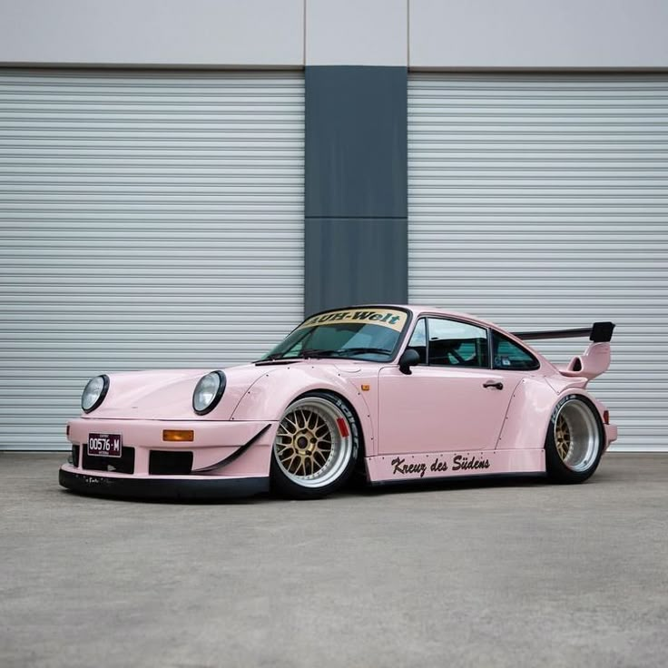 a pink car parked in front of a garage door