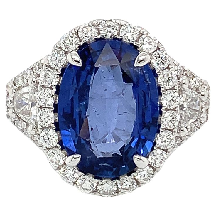 Certified 5.16 cts oval Ceylon Sapphire Measuring (13.0x9.4) mm 48 pieces of round diamonds weighing .90 cts One pair of trapezoid diamonds weighing .37 cts Set in 18K white gold ring Weighing 7.12 grams