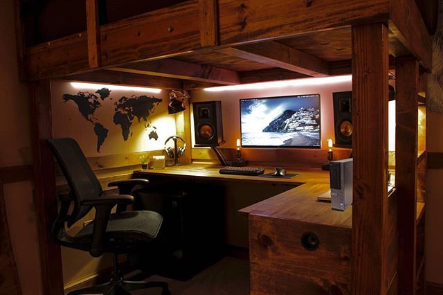 a desk with a monitor and keyboard on it in a room that has wood paneling