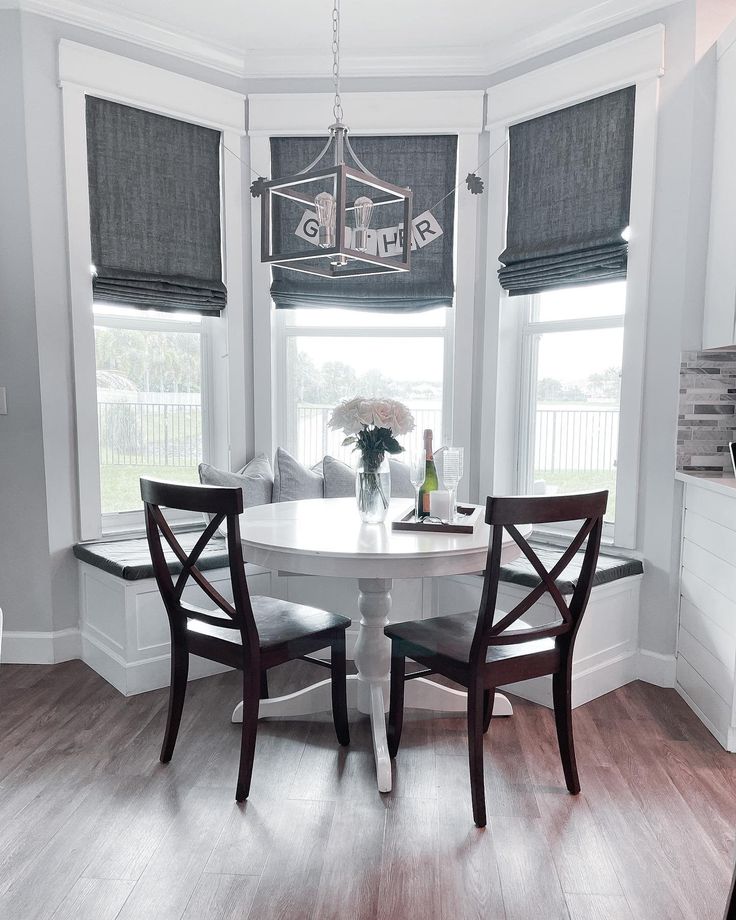 a dining room table with two chairs and a vase on the table in front of it