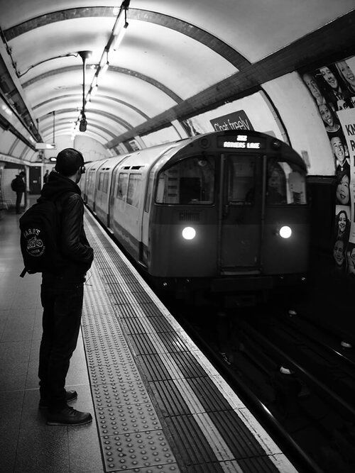 a man standing in front of a train at a subway station with his back to the camera