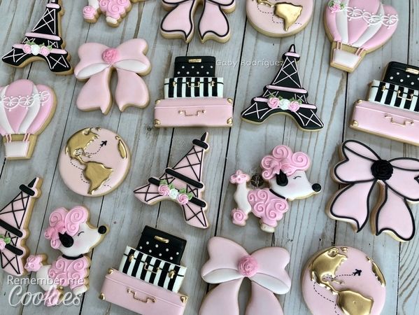 pink and black decorated cookies on a wooden table with paris themed decorations in the background