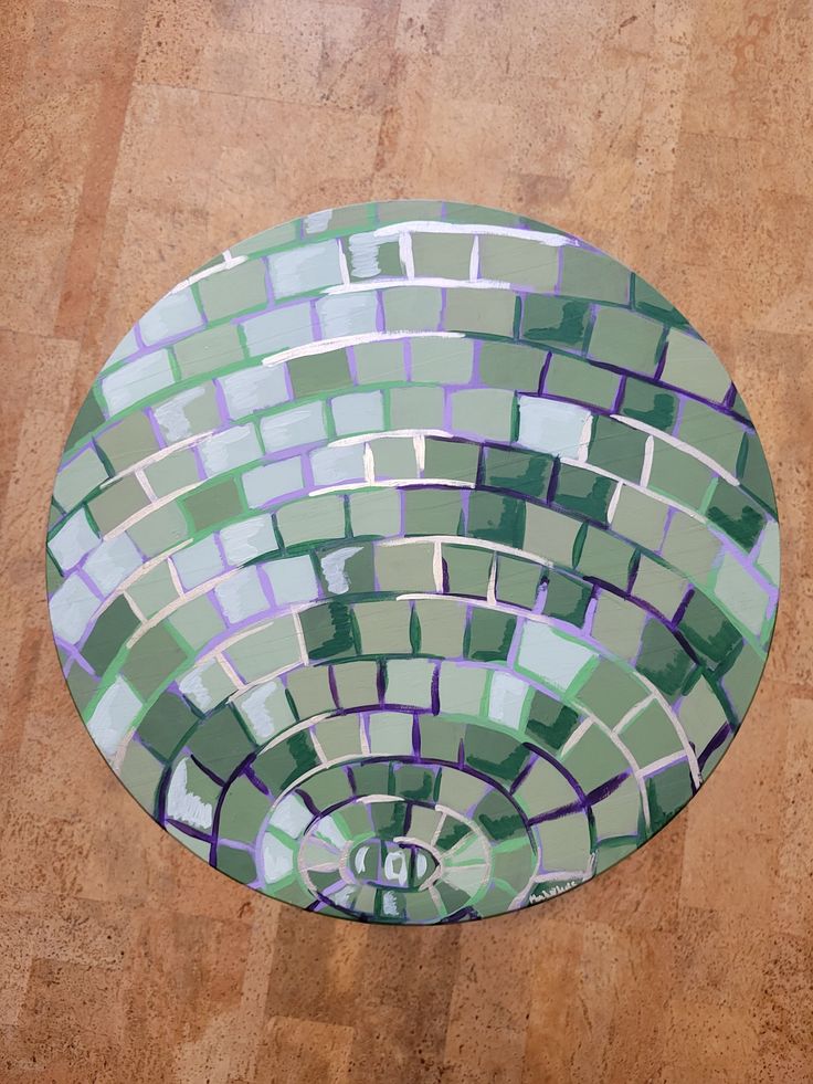 a circular mirror with green and purple tiles on it