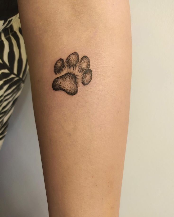 a dog paw tattoo on the right thigh, with an animal's paw in black ink