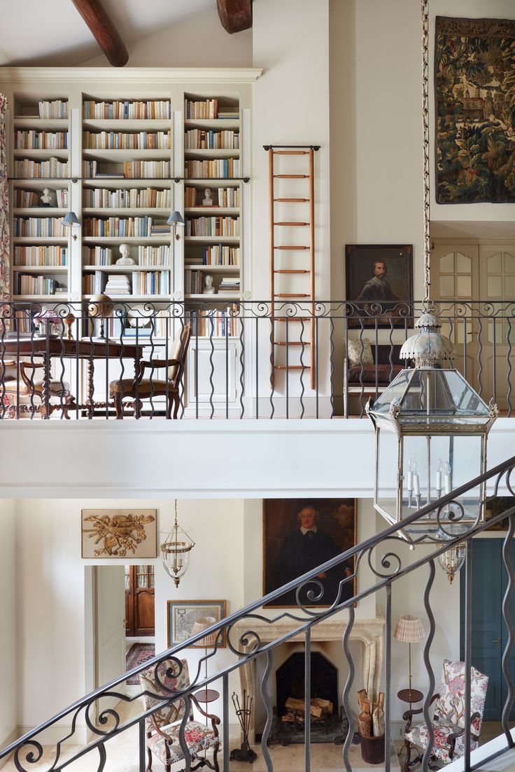 a living room filled with furniture and a fire place under a book shelf next to a stair case