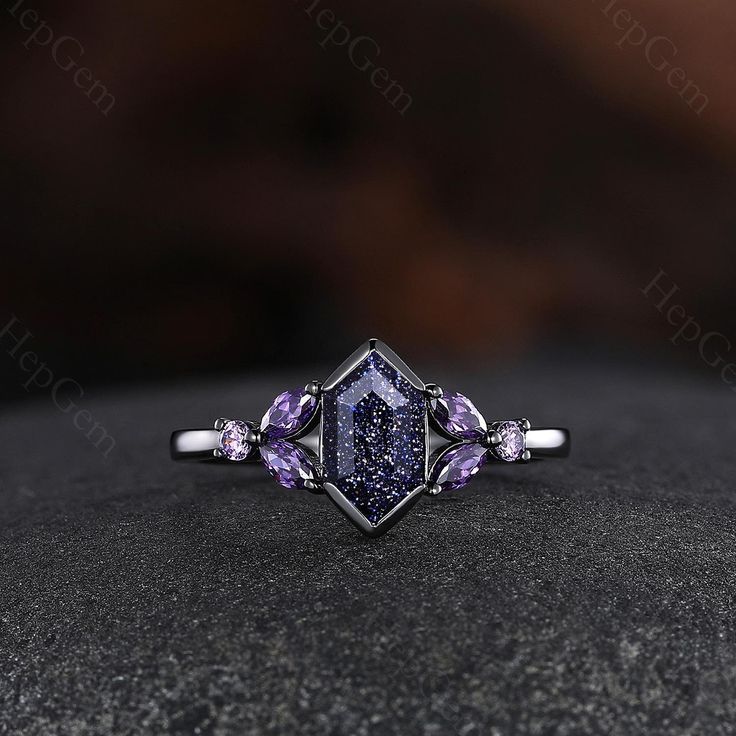 a diamond ring with purple stones in it on top of a black stone surface,