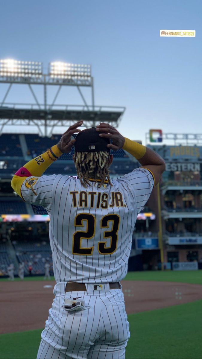 a baseball player holding his hat on top of his head in front of an empty stadium