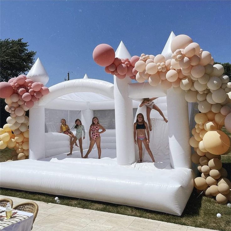 three girls are jumping on an inflatable bouncer