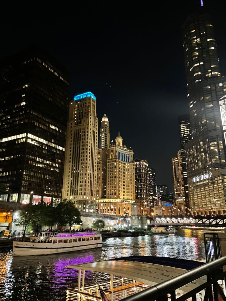 the city skyline is lit up at night with lights reflecting in the water and boats on the river