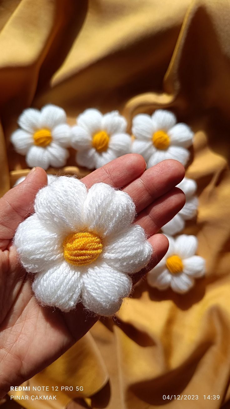 small crocheted white and yellow flowers in someone's hand