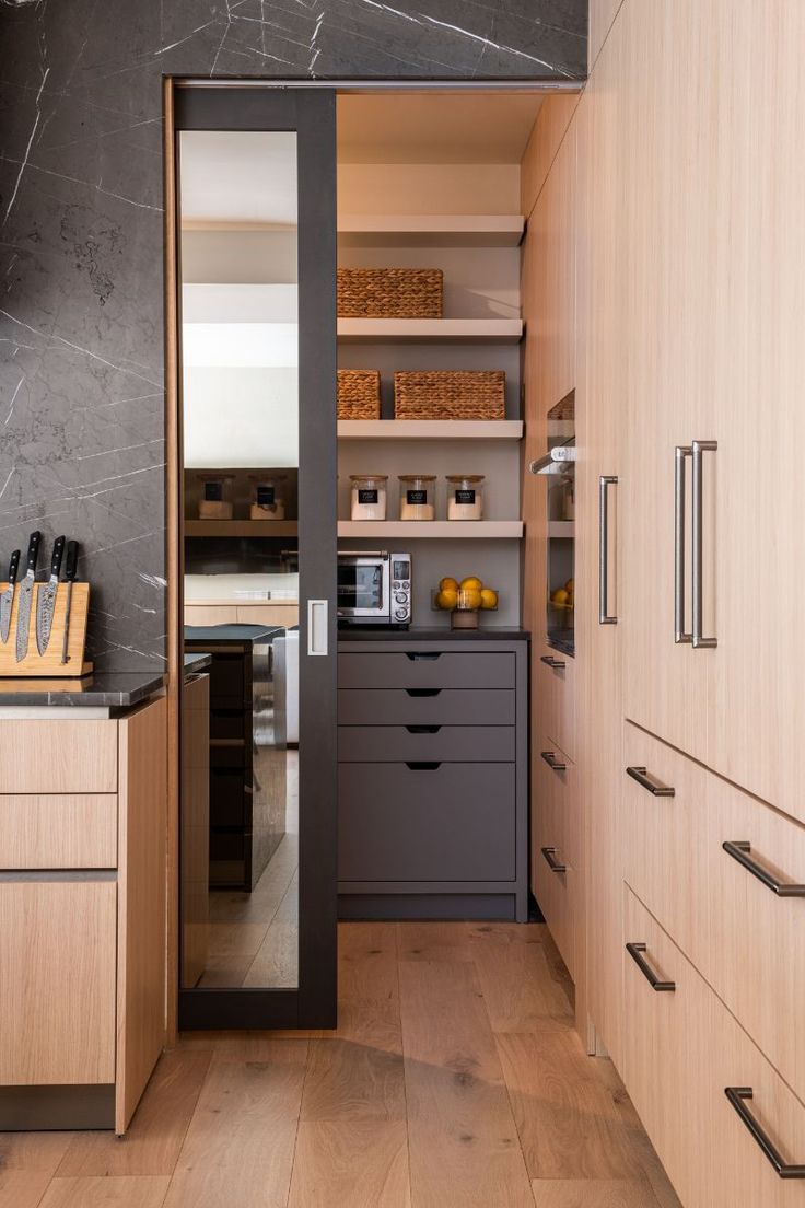 an open kitchen with wooden cabinets and black counter tops, along with gray marble walls