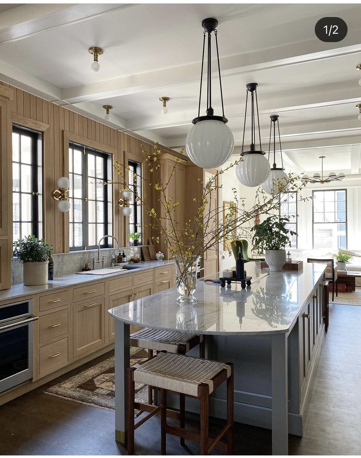 a kitchen with wooden cabinets and white marble counter tops, two pendant lights hanging from the ceiling