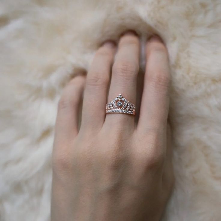 a woman's hand with a diamond ring on top of her finger and a white fur background