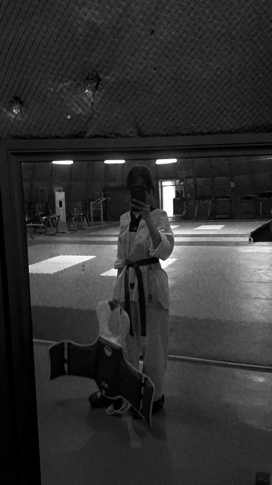 black and white photograph of a person taking a selfie in an empty parking garage