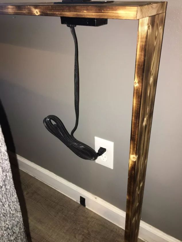 a wooden table with a black cord hanging from it's side and an electrical outlet in the middle