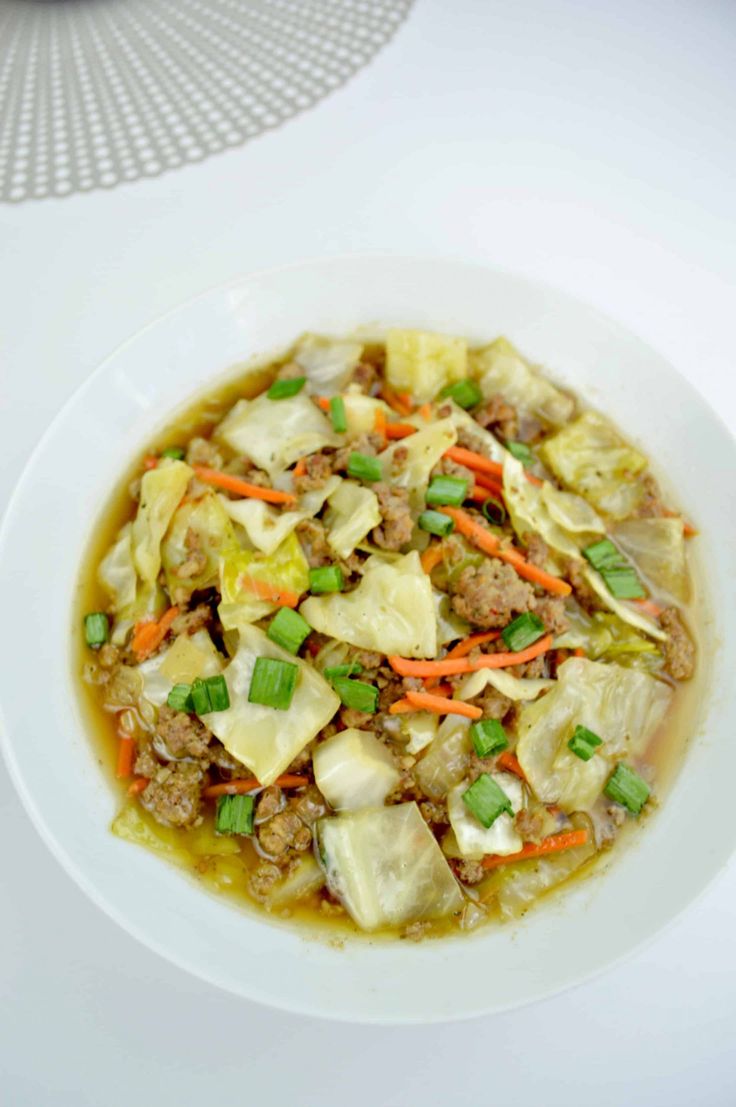 a white bowl filled with meat and vegetable soup on top of a blue table cloth