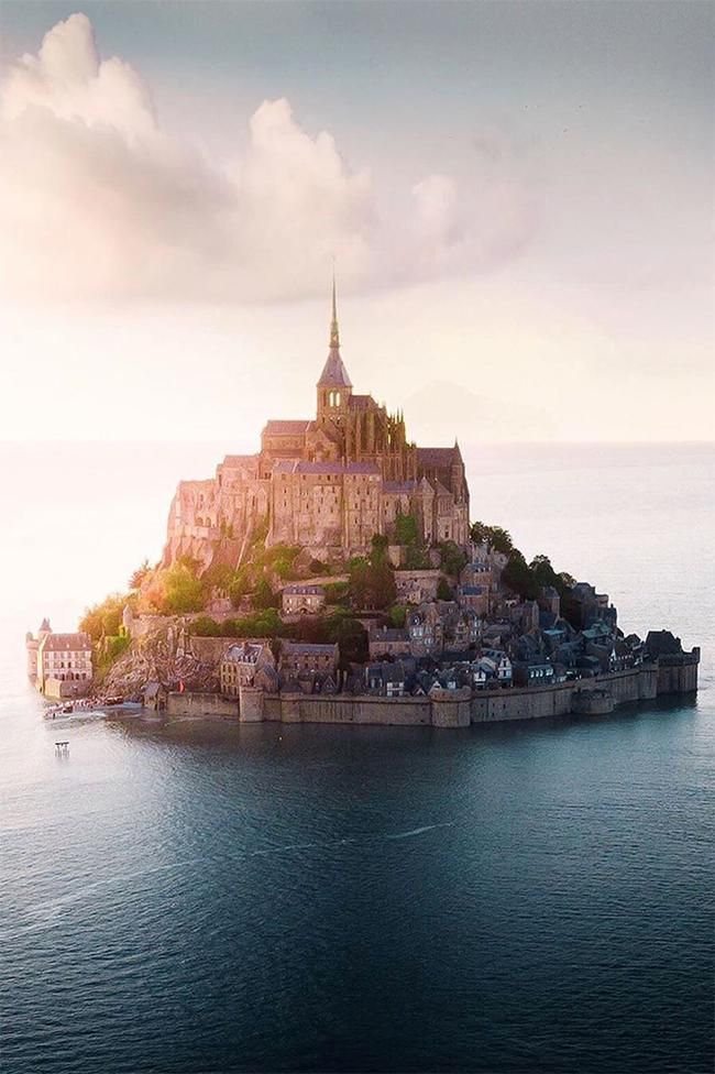 an island in the middle of the ocean with a church on it's top