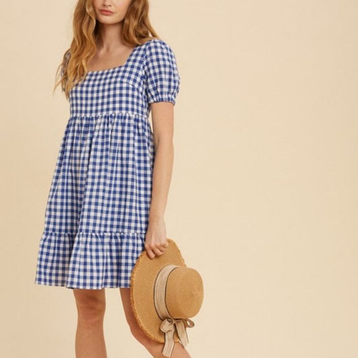 a woman in a blue and white checkered dress holding a hat