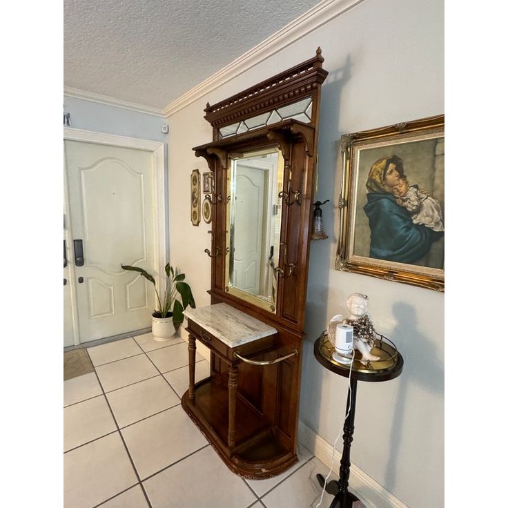 a mirror sitting on top of a wooden cabinet next to a wall mounted shelf with a painting above it