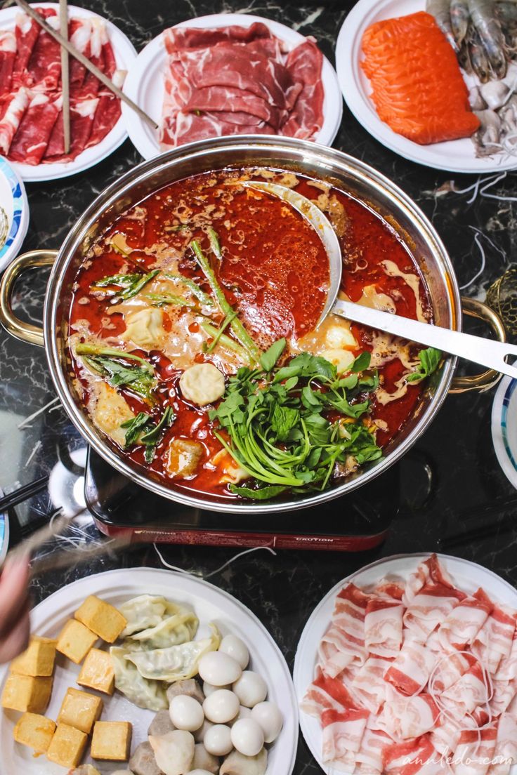 a table topped with lots of different types of meats and veggies on plates