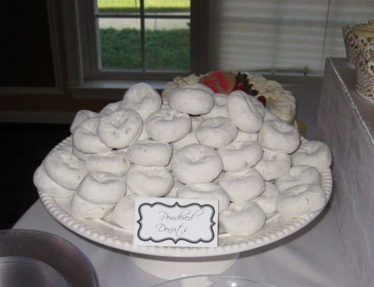 a white plate topped with lots of doughnuts on top of a cake stand