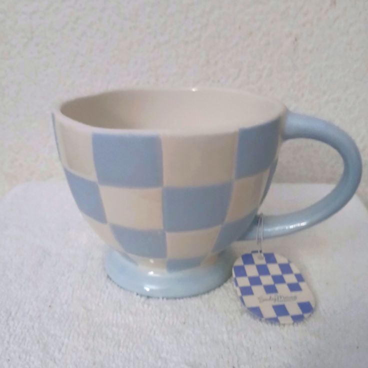 a blue and white checkered coffee cup with a tag