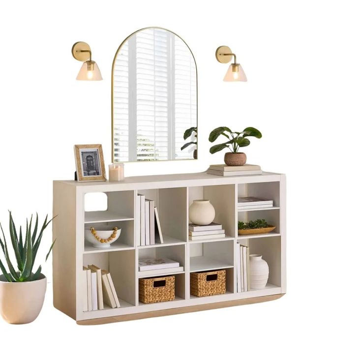 a white bookcase with books and plants on it next to a potted plant