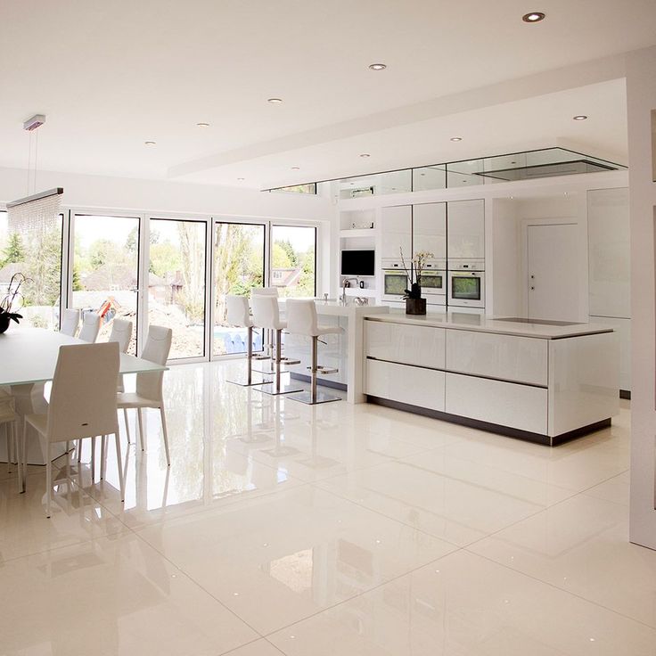 a large kitchen with white cabinets and counter tops next to a dining room table that has chairs around it