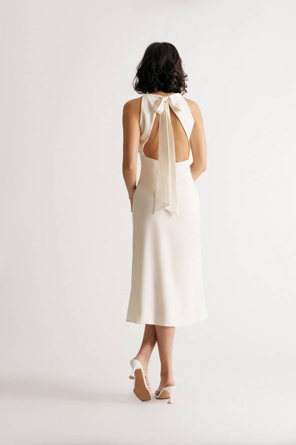 the back of a woman wearing a white dress with a bow on it's neck