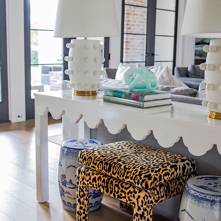 a leopard print stool sits in front of a white table with two lamps on it