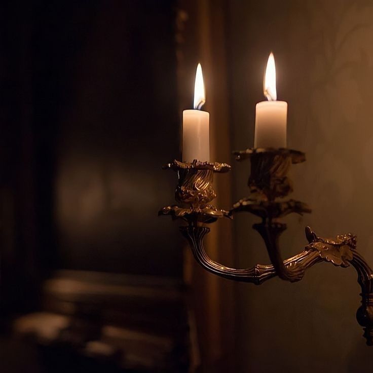 two candles are lit in the dark room