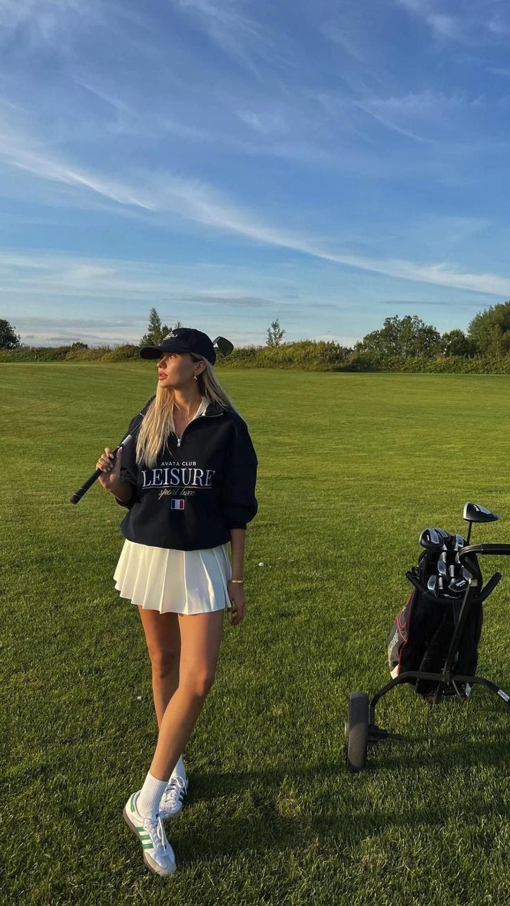 a woman standing on top of a lush green field next to a golf ball bag