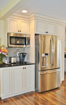 a kitchen with white cabinets, stainless steel appliances and wood floors is shown in this image