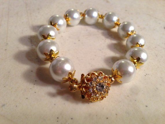 This pearl bracelet created by Jewelry By Luet and Co is made of white glass pearls, gold plated and clear crystal box clasp and gold plated beads and bead caps.  This bracelet measures 7 1/2 inches in length.All of our jewelry is unique and custom designed. We would love to assist you with any custom orders or needs for special occasions!We appreciate you shopping with Jewelry By and Luet and Co and hope you will do so often! See more items from my shop: http://www.etsy.com/shop/cdjaliFACEBOOK: White Pearl Jewelry For Celebration, Elegant Round Beads Bracelets For Celebrations, Elegant White Bracelets For Celebrations, Elegant Beaded Jewelry For Wedding Gift, Formal White Pearl Beaded Bracelets, White Beaded Bracelet For Anniversary, White Pearl Beaded Bracelet For Wedding, Elegant Gold Beaded Bracelets For Celebration, White Round Pearl Bracelet For Wedding