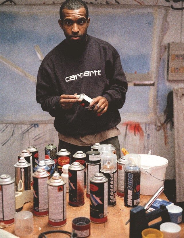 a man standing in front of a table with many cans on it and various other items around him