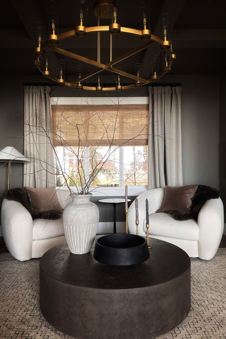 a living room with two white couches and a round coffee table in front of a window