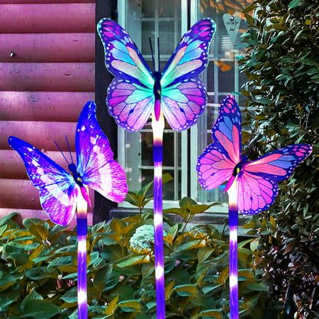 three purple and blue lighted butterflies sitting in front of a window with green plants next to it