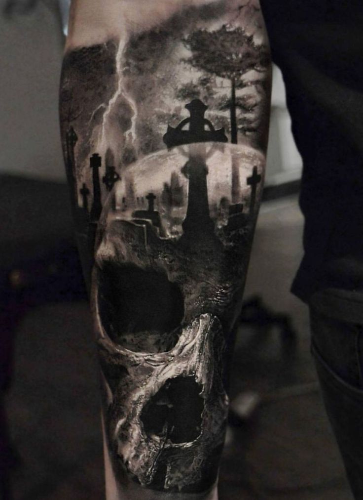 a man's leg with a skull and trees tattoo on the side of his leg