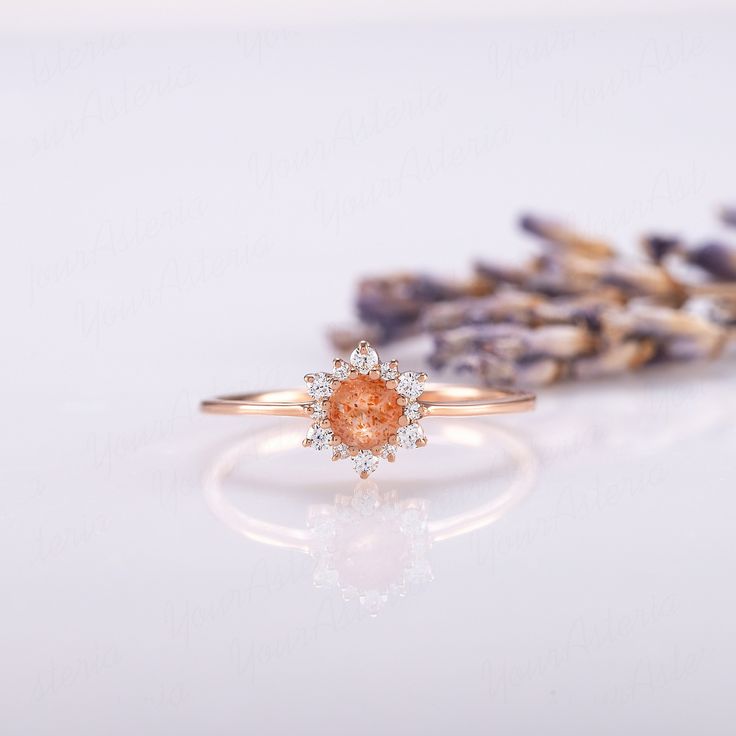 an orange diamond ring sitting next to lavender flowers