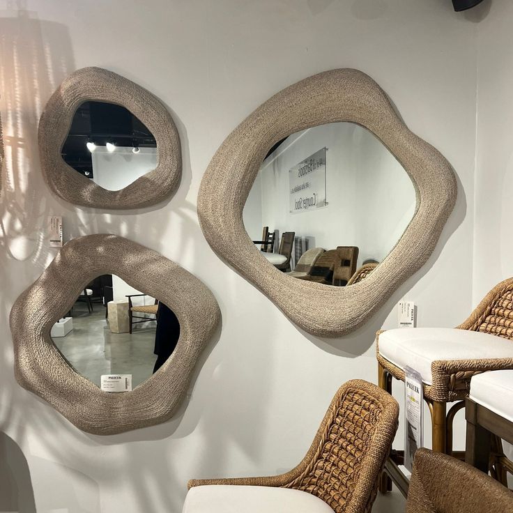 three mirrors hanging on the wall next to chairs