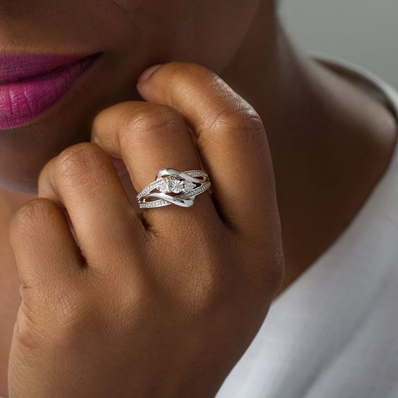 Complement any outfit with this shimmering fashion ring. Crafted in sterling silver, this graceful style features a trio of diamond accents - each artfully set to enhance size and sparkle - along the center of the design on the diagonal. Along the diamond-accented and beaded wide-split shank, polished ribbons layer over and bypass the centerpiece. Buffed to a brilliant luster, this look is certain to please. Custom-made to fit her ring size. Sterling silver rings cannot be resized after purchase Modern Twist Diamond Bypass Ring For Anniversary, Fine Jewelry Bypass Ring With Diamond Accents For Promise, Fine Jewelry Bypass Ring With Diamond Accents, Modern Twisted Diamond Ring With Accents For Anniversary, Modern Twist Diamond Ring With Accents For Anniversary, Modern Twist Promise Ring With Diamond Accents, Elegant Silver Bypass Promise Ring, Diamond Ring With Modern Twist For Gifts, Silver Bypass Ring With Diamond Accents