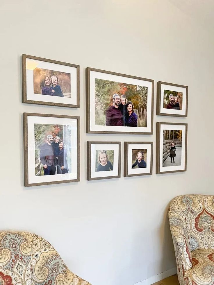 a living room with pictures hanging on the wall and two chairs in front of them