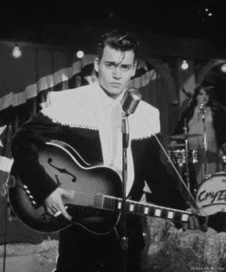 elvis presley singing into a microphone and holding an acoustic guitar in front of two other musicians