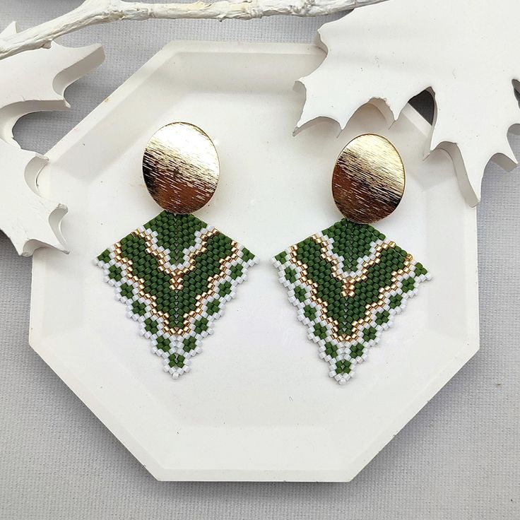 Add a touch of boho sophistication with these Avocado Green Boho Stud Earrings. Featuring a meticulously crafted pattern in avocado green, gold, and white, these earrings stand out as a unique and stylish accessory. The 18K gold-filled oval stud provides a luxurious accent, making these earrings perfect for elevating both casual and formal looks. Designed with a distinct bohemian flair, they are an ideal choice for anyone looking to add a vibrant, yet elegant, touch to their wardrobe. BEADED PAR Artisan Gold Beaded Earrings, Green Dangle Beaded Earrings With Gold Beads, Bohemian Green Earrings With Gold Beads, Artisan Green Dangle Beaded Earrings, Green Beaded Dangle Earrings For Festive Occasions, Green Artisan Dangle Earrings, Green Beaded Drop Earrings For Festive Occasions, Festive Green Beaded Drop Earrings, Gold Bohemian Beaded Earrings For Gift