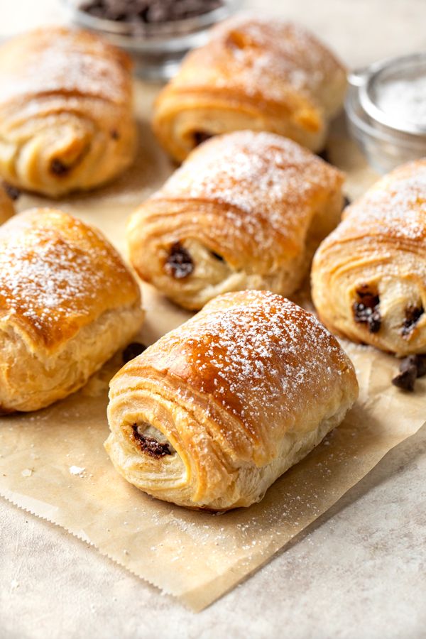 croissants with raisins and powdered sugar sit on parchment paper