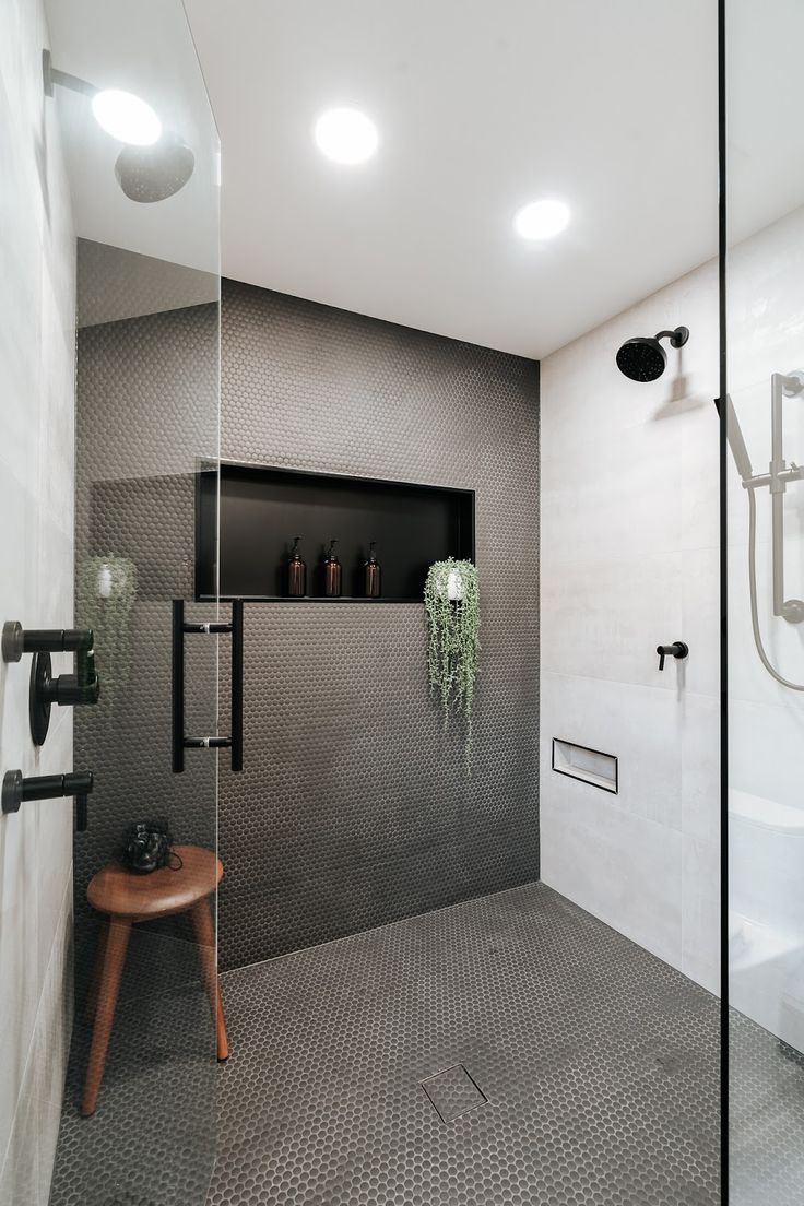 a walk in shower sitting next to a wooden stool