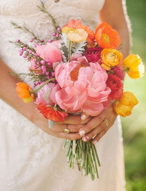 a woman holding a bouquet of flowers in her hands and wearing a wedding ring on her finger