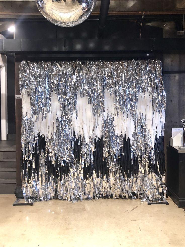 the curtain is covered with silver and black sequins in an industrial space that looks like it has been set up for a performance