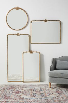 three mirrors are hanging on the wall next to a gray chair and an ornate rug